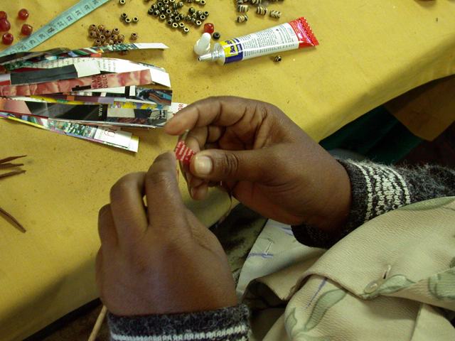 Aus in Streifen geschnittenen Hochglanzmagazinen fertigen die Frauen Perlen fr die Ketten