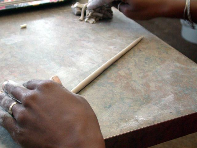 Aus einem Batzen Ton wird von Hand eine Wurst gerollt...